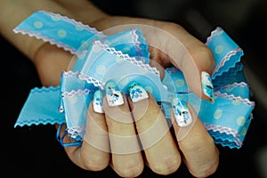 Blue manicure with a flower pattern, and a bow in hand