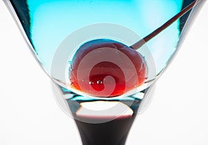 Blue martini cocktail with cherry on the rustic background