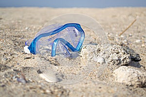 Blue mask for diving in the sand on the seashore near shells