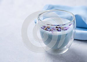 Blue matcha tea in a clear glass on a white table