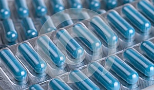 Blue medical capsules in blisters isolated. Selective focus.