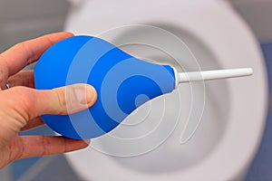 Blue medical enema on the background of a white toilet