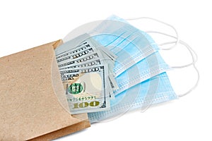 Blue medical face masks and stack of 100 USD banknotes in brown paper packet isolated on white background