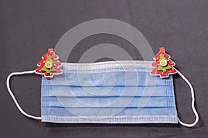 Blue medical mask with christmas tree-shaped clothespins. new years medical flatly photo