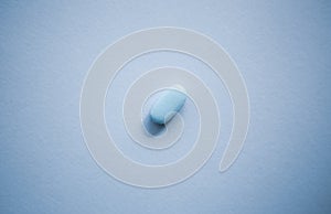 Blue medical pill on empty colorful background shot in flat lay style