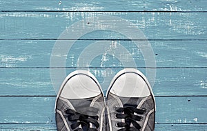 Blue men`s old shabby sneakers on a blue wooden surface