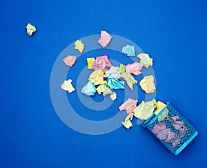 Blue metal bucket filled with crumpled multi-colored white paper