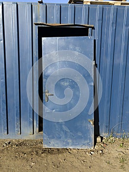 Blue metal hangar, door removed from its hinges and leaned against the entrance