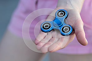 Blue metal popular fidget spinner toy on the palm of your hand, anxiety relief toy, anti stress and relaxation fidgets