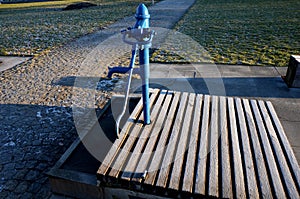 Blue metal retro well with polished elegant wooden lid. water flows from the hand pump into the stone trough. garden bench shaped