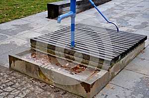 Blue metal retro well with polished elegant wooden lid. water flows from the hand pump into the stone trough. garden bench shaped