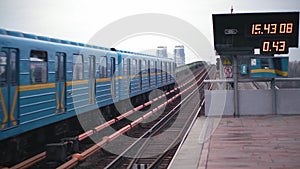 The blue metro train arrives at the ground station on the bridge across the wide Dnieper River in Kiev.