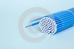 Blue microbrushes, small brushes for cleaning eyelashes and teeth. Blue background. Dentistry, eyelash extensions