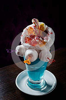 Blue milkshake with donuts stands on the table in the cafe on dark background