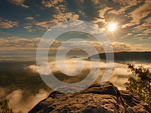 Blue misty daybreak. Sandstone cliff above deep foggy valley in mountains.