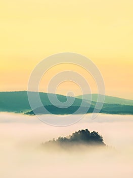 Blue misty morning, view over rock to deep valley full of light mist. Dreamy spring landscape within daybreak