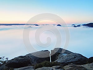 Blue misty morning, view over rock to deep valley full of light mist. Dreamy spring landscape within daybreak