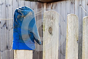 Blue mitten worn on the fence.