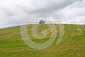 Blue modern tractor pulling a crop sprayer on a hill