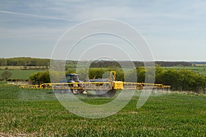 Blue modern tractor pulling a crop sprayer