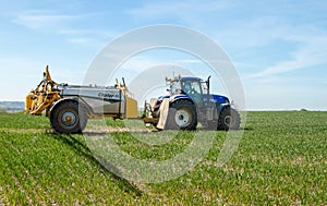 Blue modern tractor pulling a crop sprayer