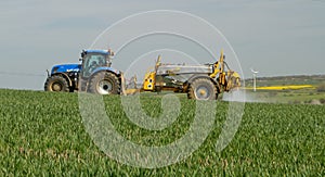 Blue modern tractor pulling a crop sprayer