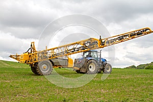 Blue modern tractor pulling a crop sprayer