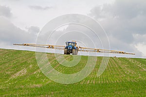 Blue modern tractor pulling a crop sprayer