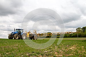 Blue modern tractor pulling a crop sprayer