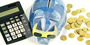 Blue money box between coins pile and outdated calculator