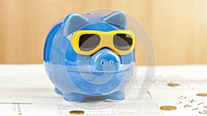 Blue money box of pig form with sunglasses stands on table