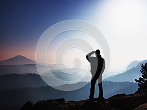 Blue morning. Hiker is standing on the peak of rock in rock empires park and watching over misty landscape.