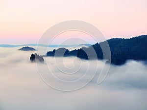 Blue morning, view over rock to deep valley full of light mist. Dreamy spring landscape within daybreak