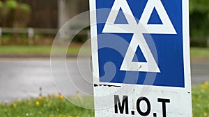 Blue MOT service sign on british road on cloudy rainy day photo