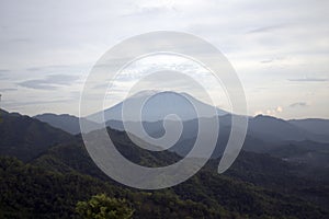 Blue mountains in clouds at sunrise in summer. Natural Bali mountain landscape background.