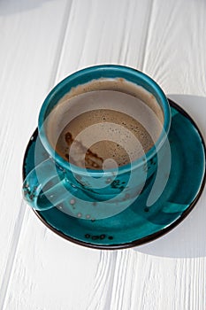 Blue mug with coffee, cappuccino on a white wooden background. Top view