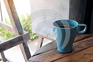 A blue mug of hot coffee on vintage wooden table in cafe