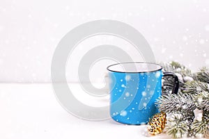 Blue mug with hot tea, coffee or cocoa and fir tree branches on white textured background