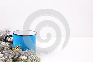 Blue mug with hot tea, coffee or cocoa and fir tree branches on white textured background