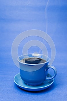 Blue mug with steaming hot coffee. Soft smoke. Blue background. photo