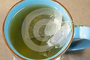 Blue mug with water and two green tea bags