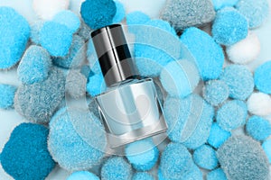 Blue nail polish bottle on blue soft pompons background. Blue nail polish bottle decorated with soft pompons photo