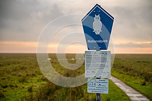 Blue National park sign near Boehler lighthouse at St. Peter Ording, germany, north sea during sunset, horizontal shot