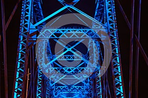 Blue neon lights illuminating upward truss crossing beams of railroad bridge in Ohio at night