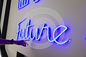Blue neon signs FUTURE BEGINS HERE in English and Arabic on wall