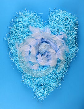 blue nest with Easter eggs with feathers on blue background