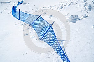 Blue net fence in snow mountain on sunny day