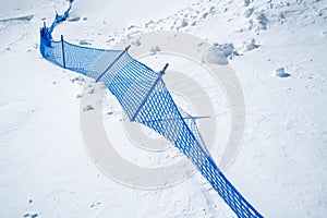 Blue net fence in snow mountain on sunny day