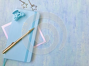 Blue new diary with golden 2021 words, golden pen, blue hairpin, golden jewelry, blue background