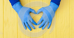 Blue Nitrile gloves. Hands of a medic in the blue latex gloves on yellow wooden table banner